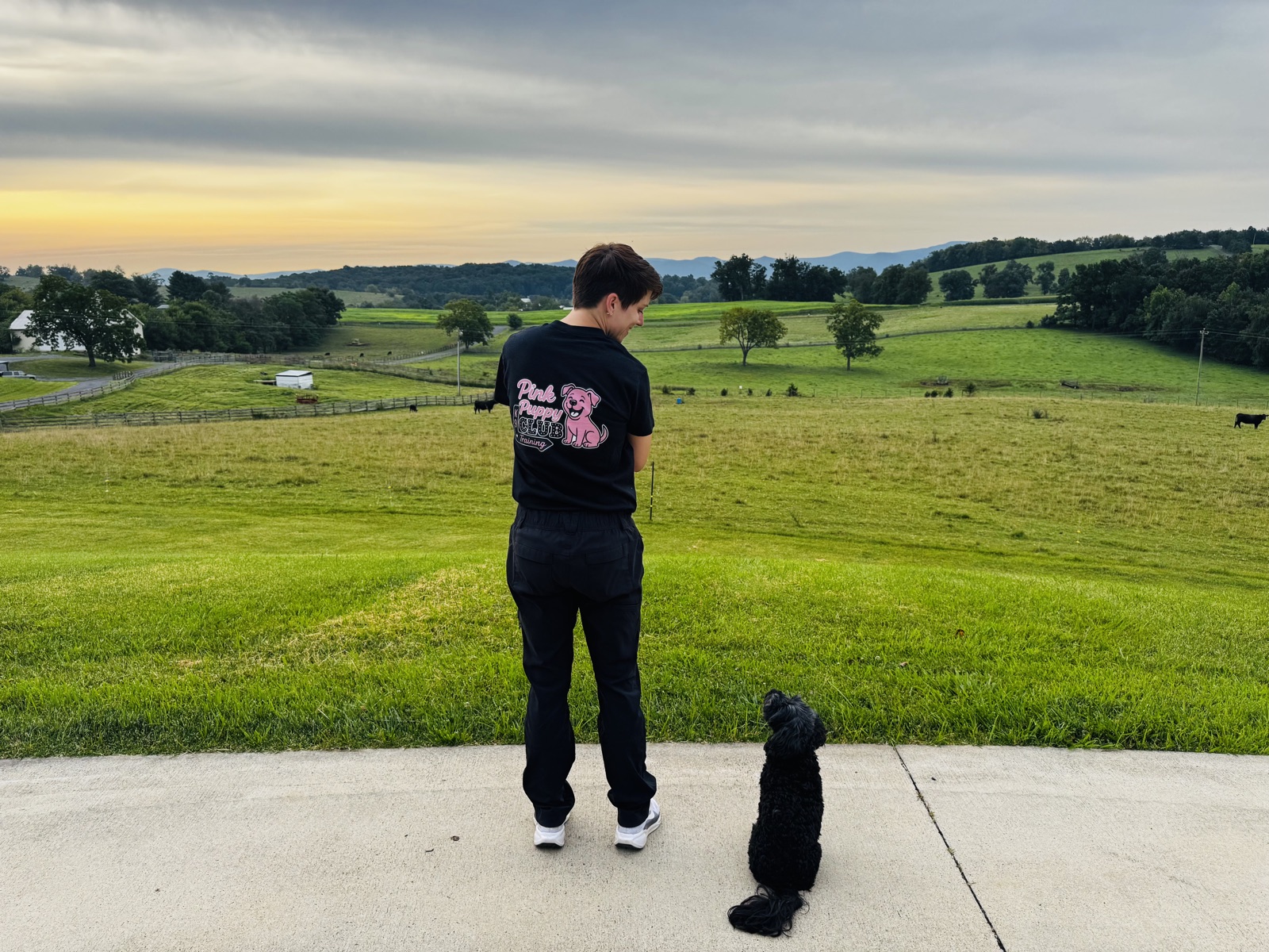 Shanda, Club Director, standing with a dog on the farm at sunset